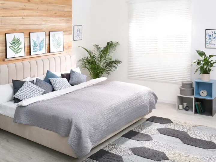 bedroom with wood feature wall and palm plant next to bed