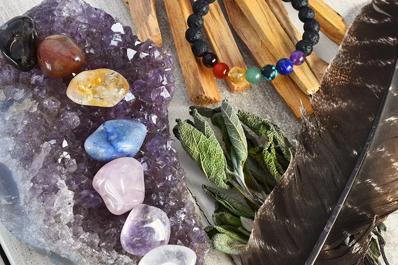 chakra stones on top of amethyst crystal next to chakra healing bracelet