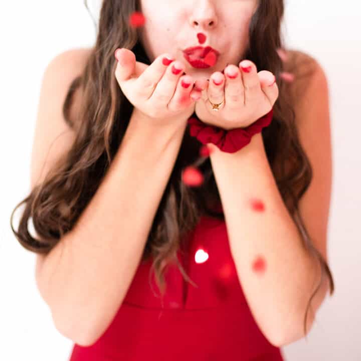 woman blowing heart confetti out of hands
