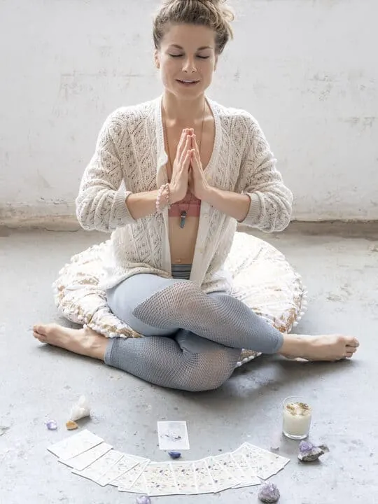 woman meditating in front of tarot cards