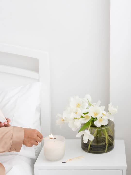 woman lighting candle on nightstand