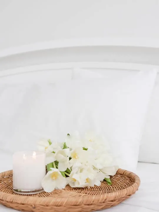 flowers and candle on tray on top of bed