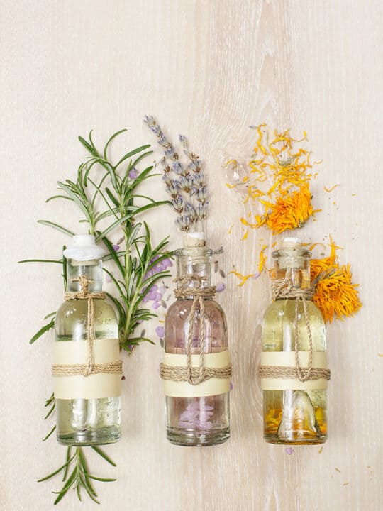 three bottles with herbal infusions - rosemary, lavender, and calendula
