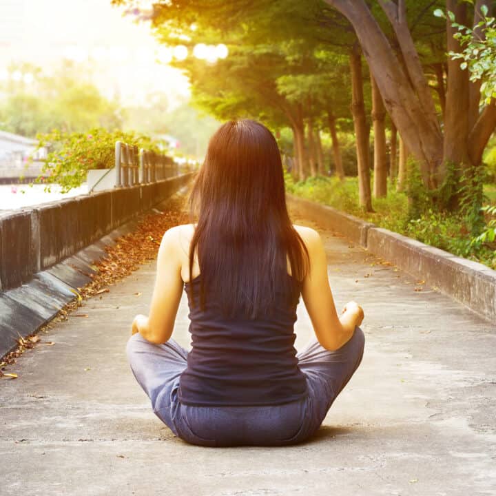 how to let go of your manifestation (woman meditating in park)