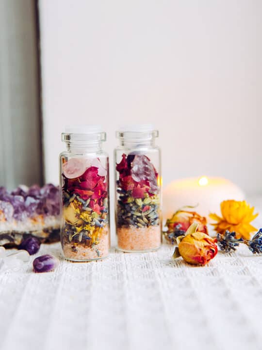 jars of dried flowers next to candles and crystals