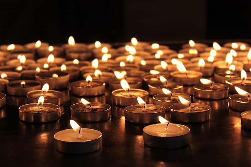 group of burning tea light candles in the dark