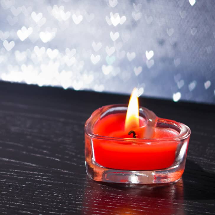 red candle in heart-shaped glass container