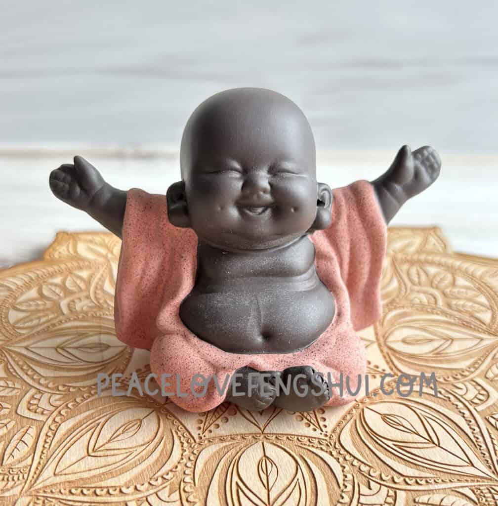 laughing buddha feng shui statue on wood crystal grid