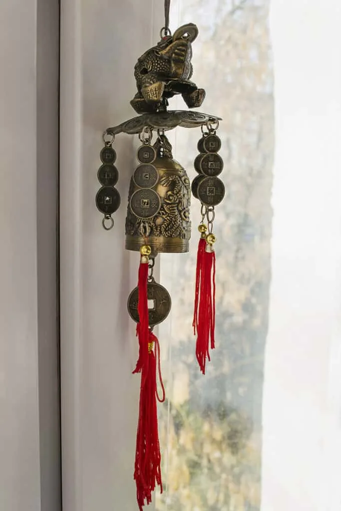 feng shui wind chimes with red string, feng shui coins, bells, and a feng shui frog