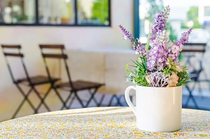 fake flowers in a white cup on a table