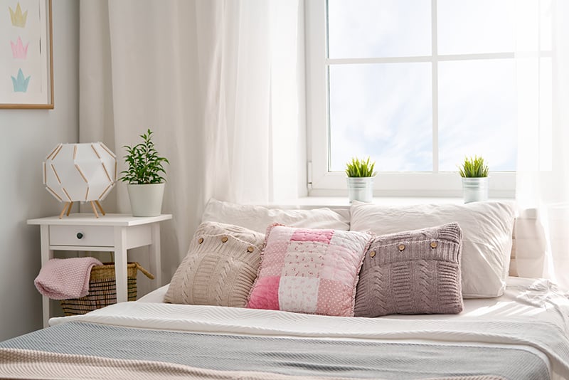 bed with cozy pillows and plants