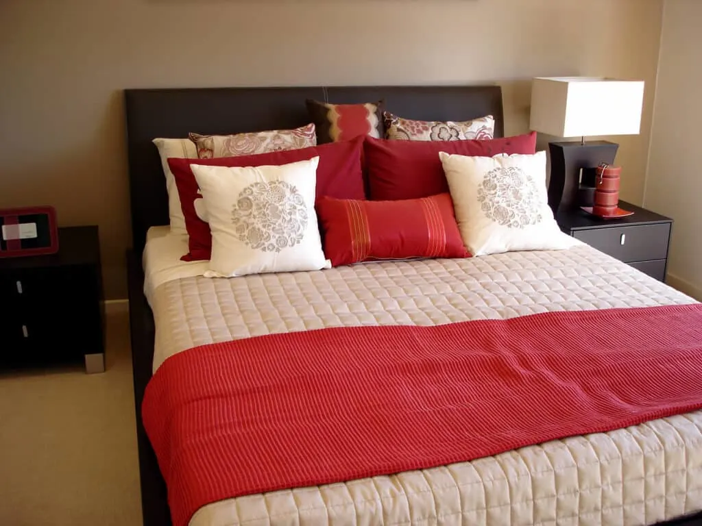 bed with red blanket and pillows