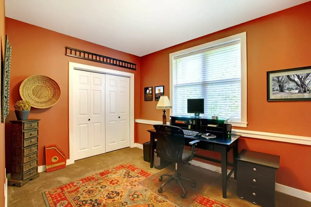 home office with orange walls and colorful rug