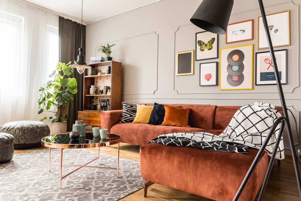 living room with burnt orange couch surrounded by neutral decor