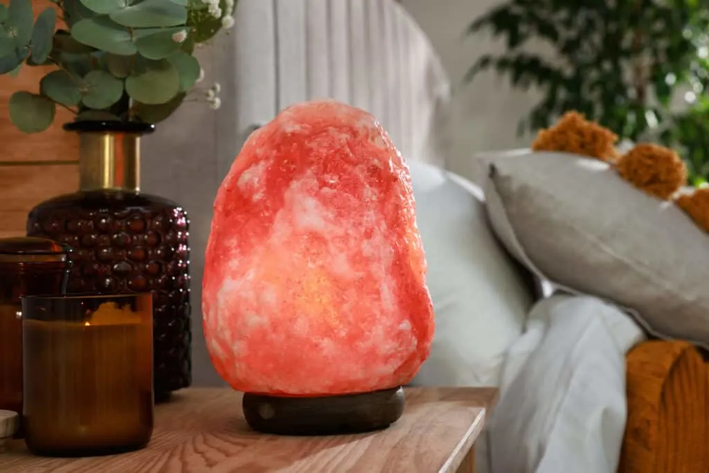 Himalayan salt lamp on night stand next to bed