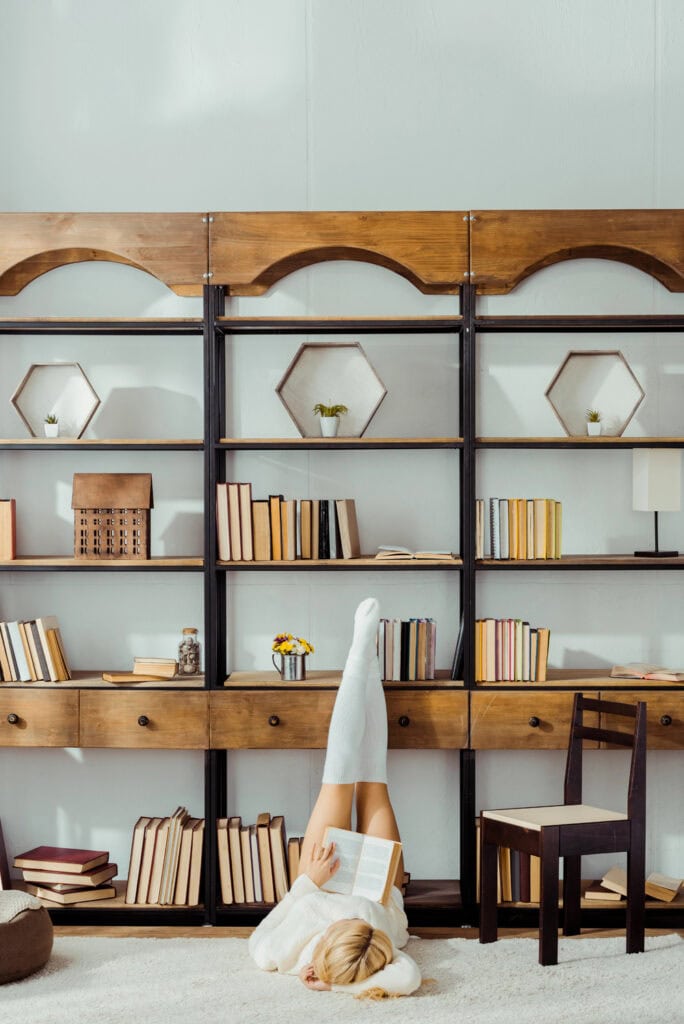 woman reading a book in front of a bookcase